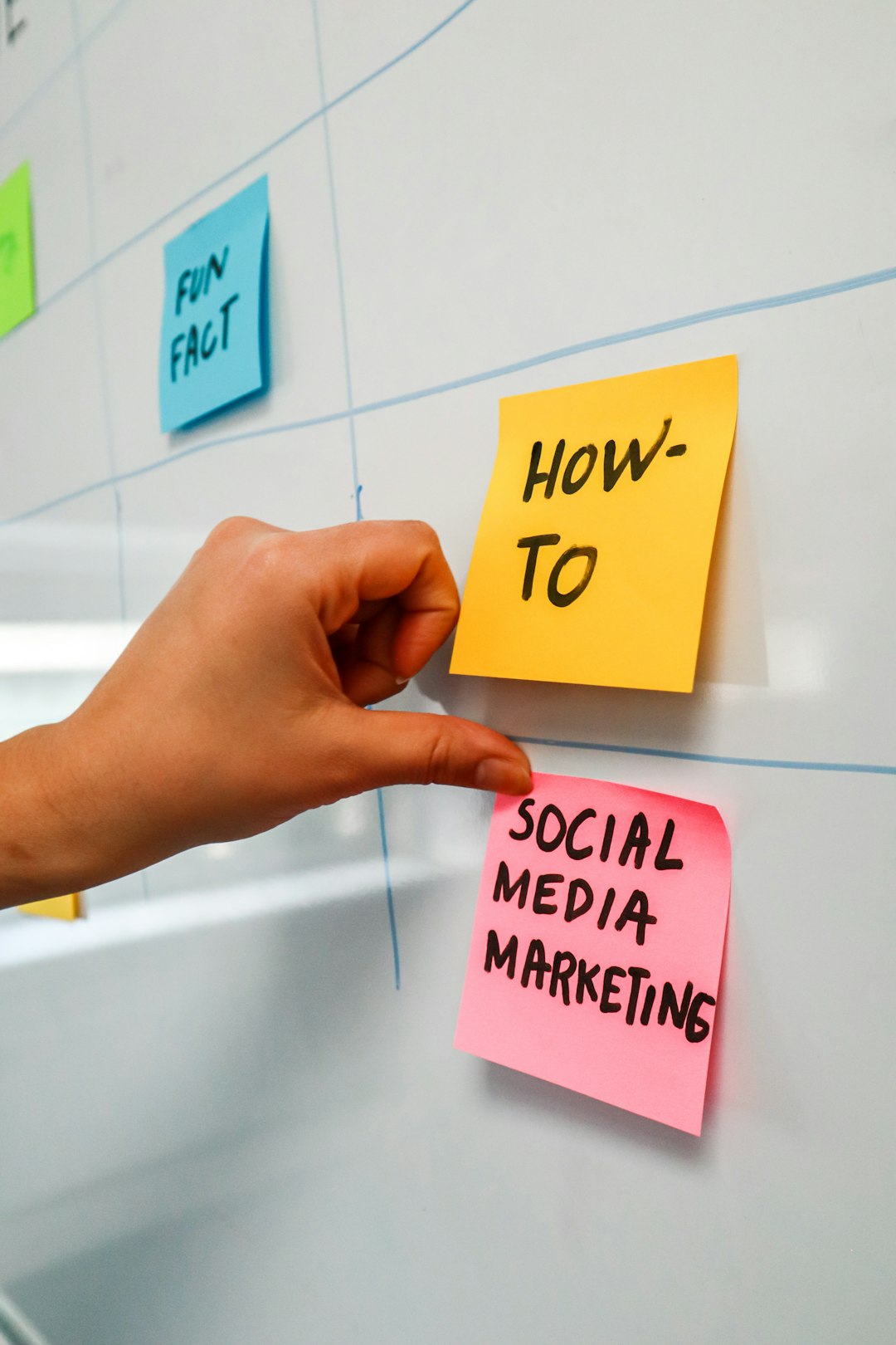 Personne collant un post-it sur un tableau blanc avec les mots Social Media Marketing écrits dessus